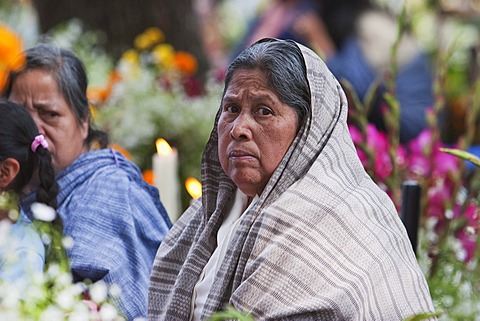 Woman by a grave during the celebration of D√É¬≠a de los Muertos, the Day of the Dead at the San Jer√É¬≥nimo Purenchecuaro cemetery. People decorate the graves of their loved ones with offerings of flowers, particularly marigolds (cempoalx√É