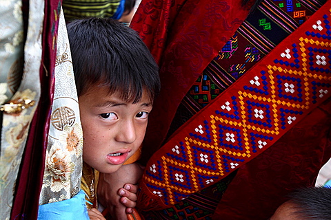 Child appearing from two women at the Thimphu festival tsechu, Bhutan