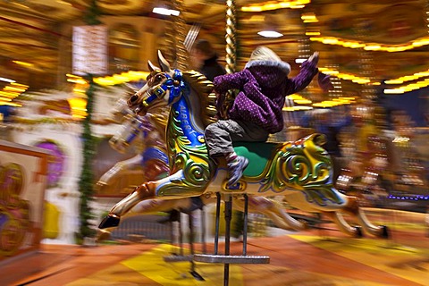 Child enjoying Merry-go-round carousel at Christmas fairground and market, Winter Wonderland, in Hyde Park, London