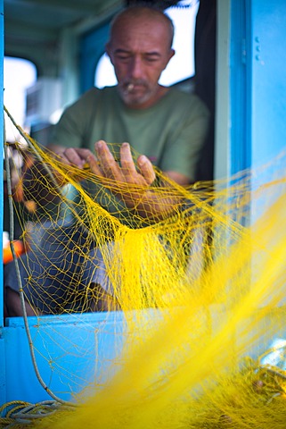 Fisherman cleaning his nets, Mykonos, Greek Islands, Greece, Europe