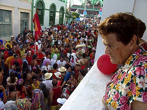 Brazil carnival. Crowd of revellers in the street during carnaval of olinda, pernambuco. Old lady looks on