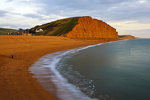 A lone fisherman stands on the beach at West Bay, Jurassic Coast, UNESCO World Heritage Site, Dorset, England, United Kingdom, Europe