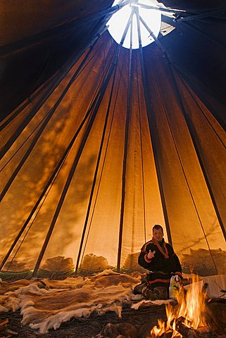 Sami reindeer herder inside his lavvu tent, Giron Siida homestead, Kiruna, arctic Sweden, Scandinavia, Europe