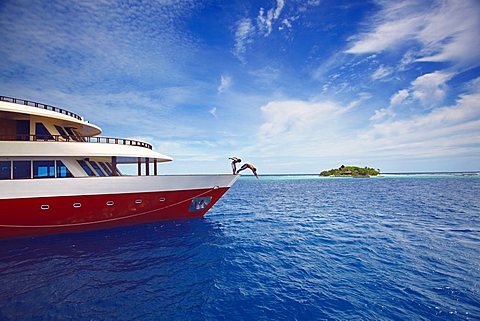 Young people jumping from boat into sea, Maldives, Indian Ocean, Asia