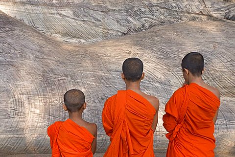 Three young monks praying at a rock-cut image of the Buddha in the Gal Vihara, Polonnaruwa (Polonnaruva), UNESCO World Heritage Site, Sri Lanka, Asia