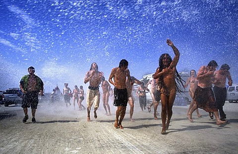 Men and Women follow a truck spraying water at Burning Man in the Black Rock Desert, Nevada on August 29, 2002.  Burning Man is an art festival that celebrates free expression.  In 2002 about 29,000 people attended the festival that started in 1986 when La