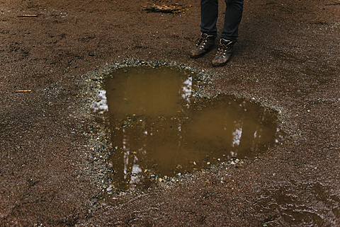 Low section of person standing by heart shaped puddle