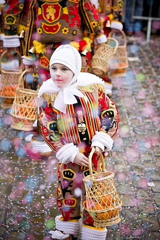 A young Gille reaches into his basket for an orange to throw to the crowd during the Carnival of Binche, Belgium.