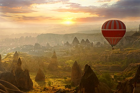 Hot air balloon over volcanic tuff rock formations at dawn, Goreme, Cappadocia, Turkey