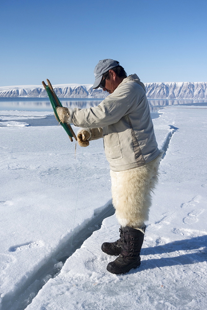 Inuit hunter line fishing at the floe edge for Arctic cod, sculpin and halibut near Herbert Island